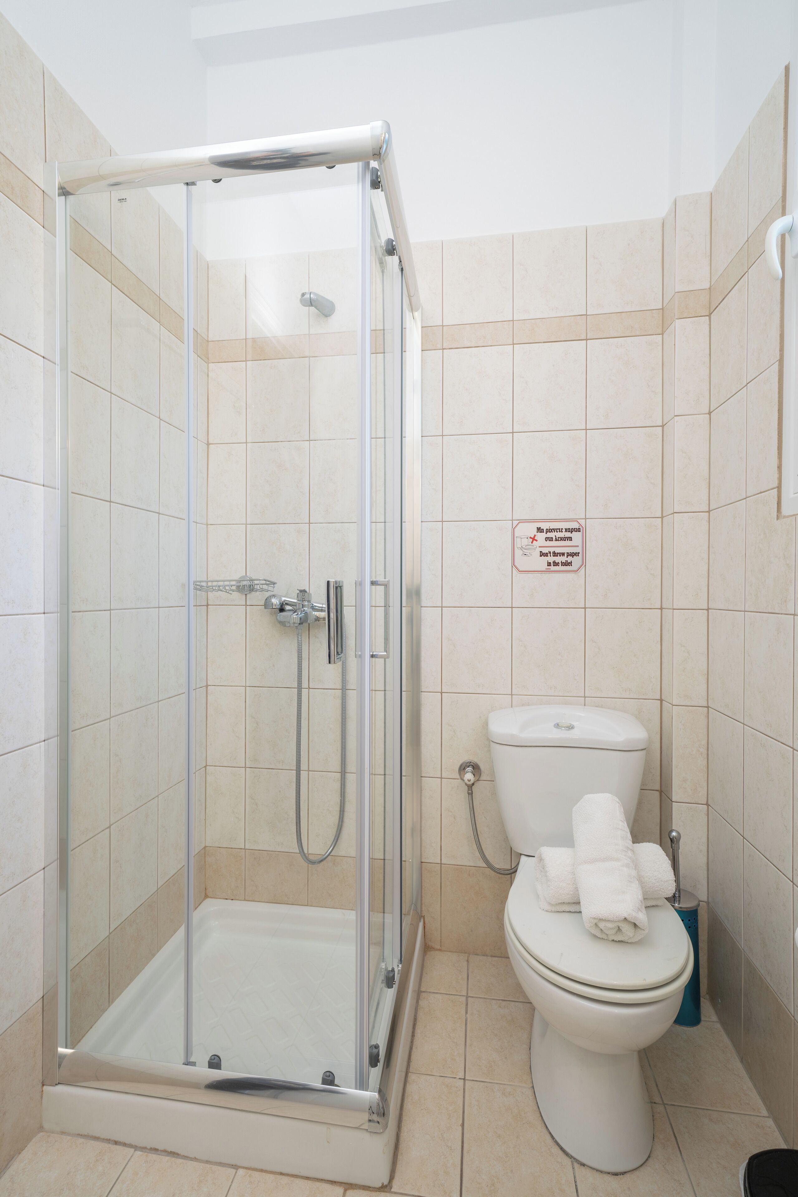 Ein Badezimmer mit einer Duschkabine, einer Toilette und einem Schild an der Wand.