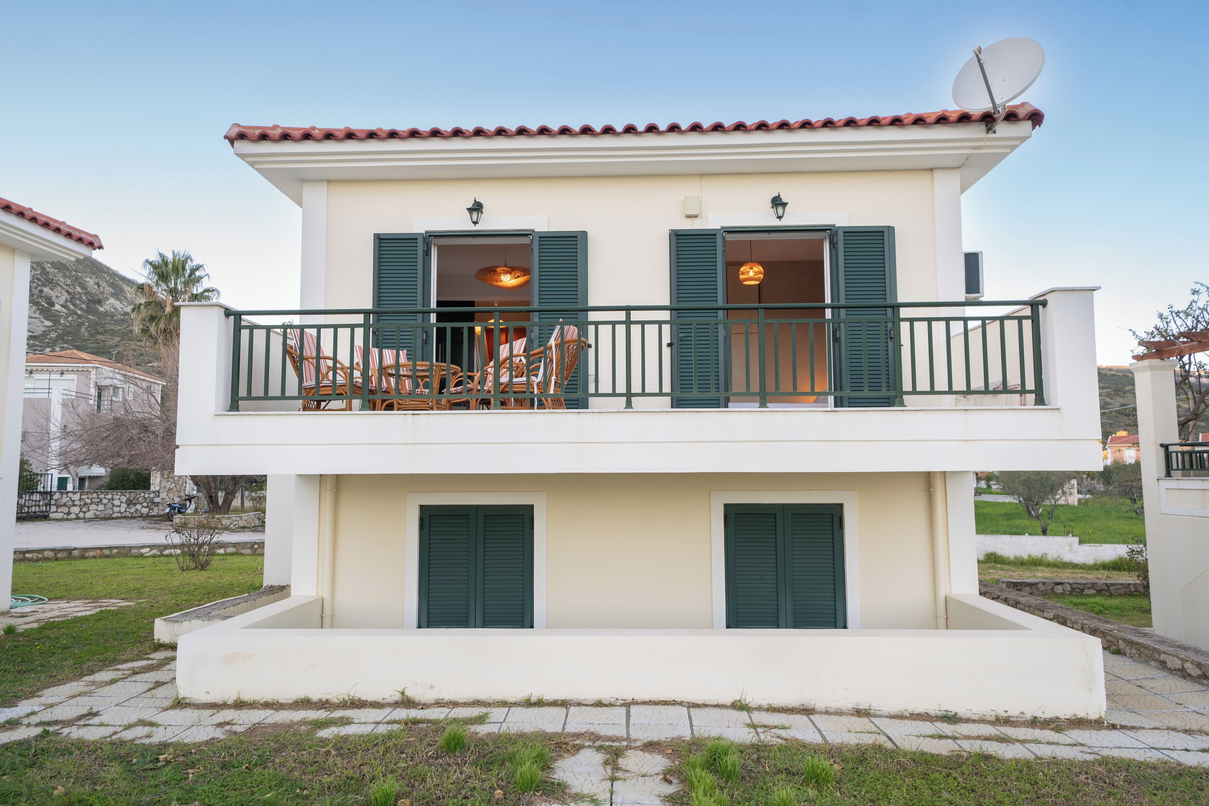 A two-story building with a balcony, green shutters, and a satellite dish.