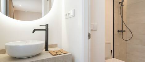 A modern bathroom with a round mirror, a white sink, and a shower enclosure.