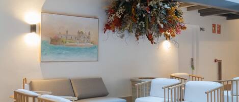 Un interior moderno con un sofá, sillas y un arreglo floral colgante.