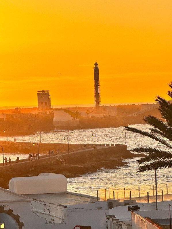 Un paisaje costero con un faro, un muelle y un edificio con el rótulo "ALETA".