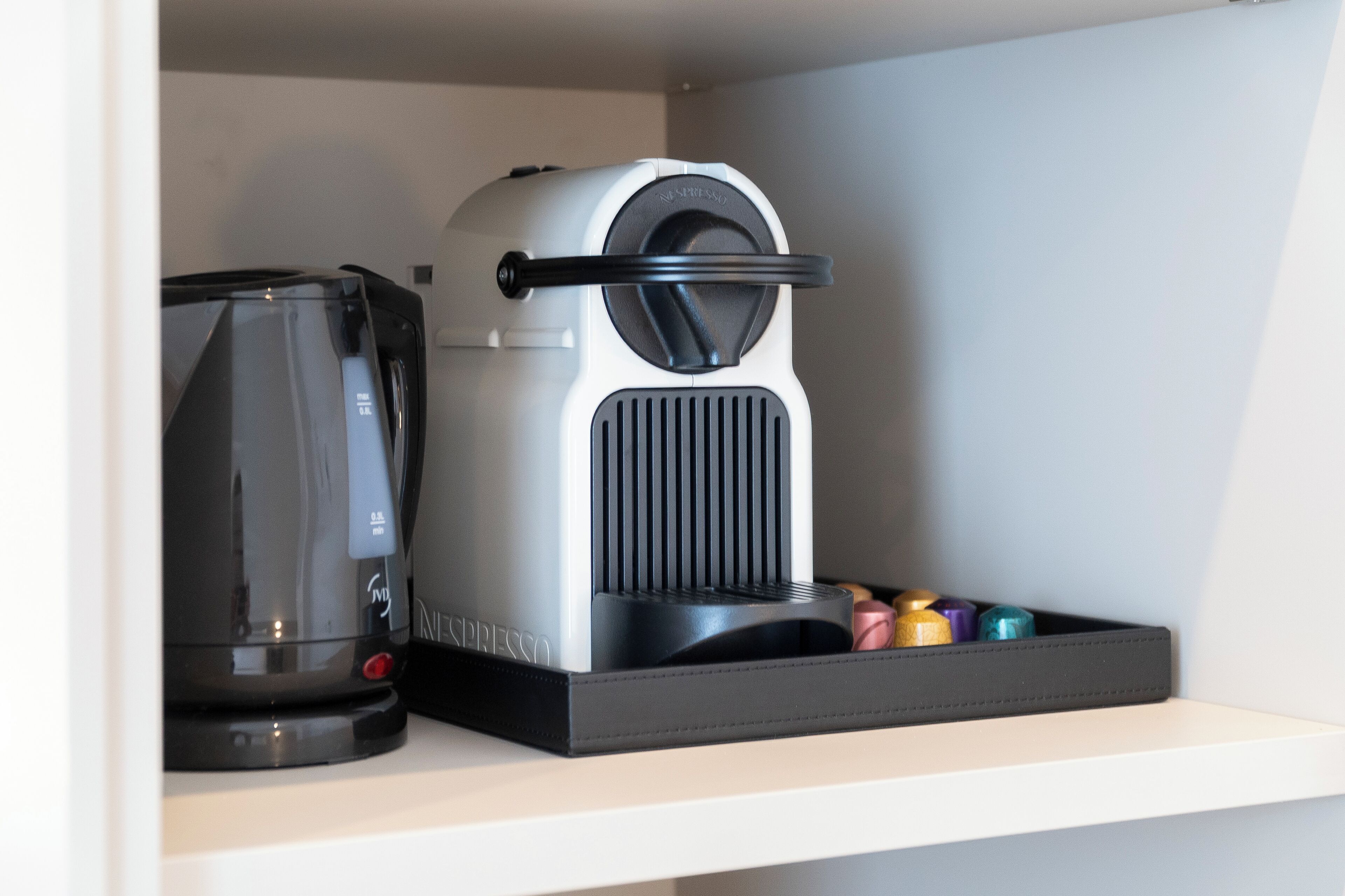 Une machine à café et une bouilloire sont posées sur une étagère.