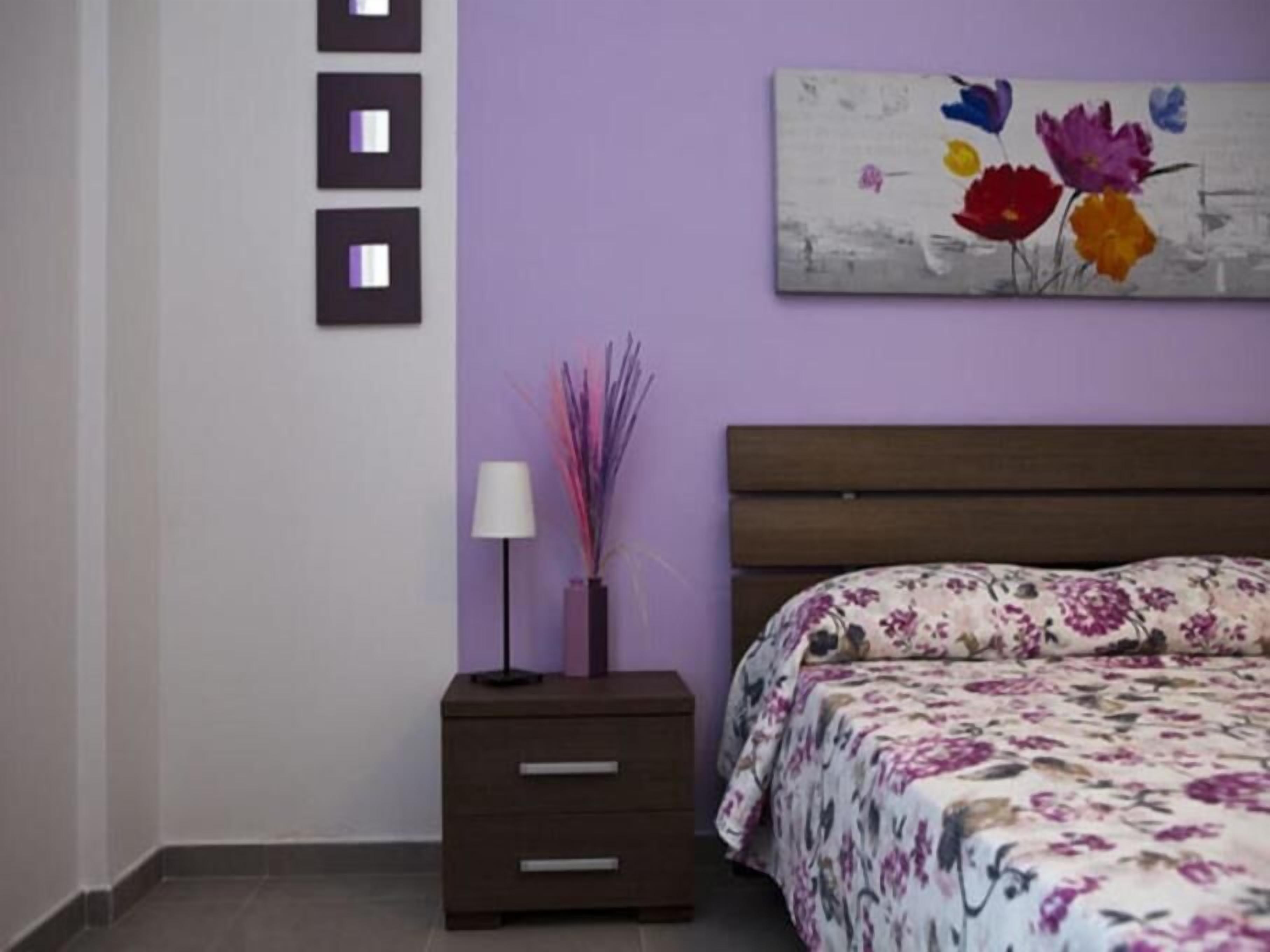 Une chambre à coucher avec un lit, une table de chevet, une lampe et un tableau accroché au mur.