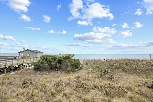A beach house with a wooden deck and a view of the ocean.