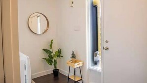 A hallway with a potted plant, a small wooden table, and a round mirror on the wall.