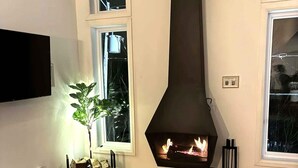 A modern living room with a fireplace, a dining table, and a TV mounted on the wall.