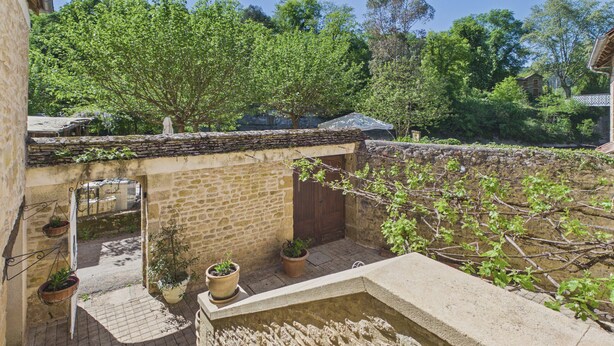 A stone courtyard with potted plants, a small pool, and a stone wall. - Stone house at the foot of La Vézère, for 6 (Saint-Léon-sur-Vézère)