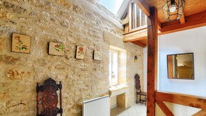 A rustic stone wall with framed botanical prints, a wooden chair, a radiator, and a wooden beam structure. - Stone house at the foot of La Vézère, for 6 (Saint-Léon-sur-Vézère)