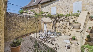 A stone building with a courtyard, outdoor seating, and potted plants. - Stone house at the foot of La Vézère, for 6 (Saint-Léon-sur-Vézère)
