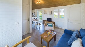Un vaste espace de vie doté d’un plafond en bois, d’un canapé bleu, d’une table basse en bois et d’une table à manger avec des chaises.