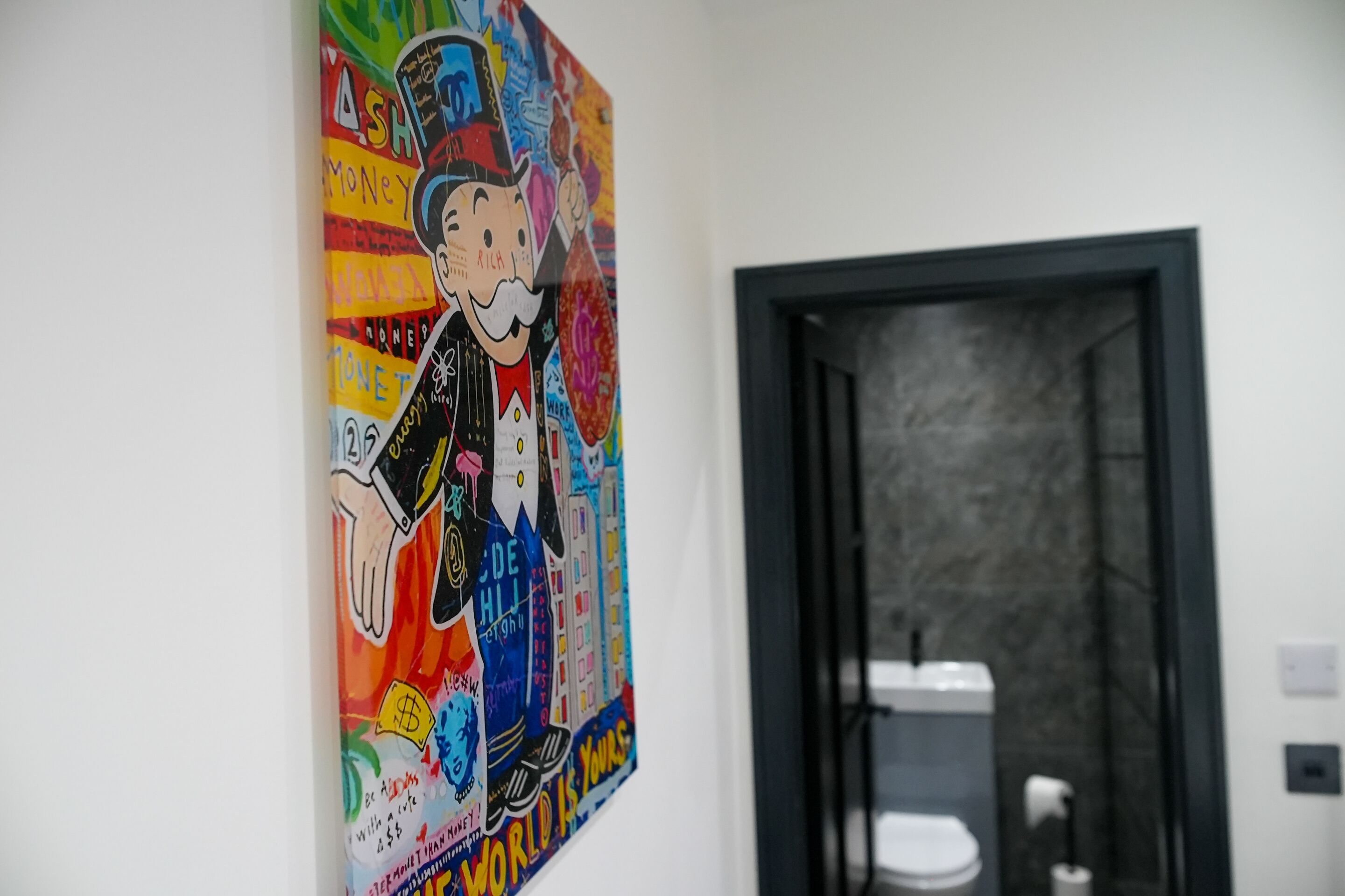 Een kleurrijke muurschildering op een muur met een deur naar een badkamer.