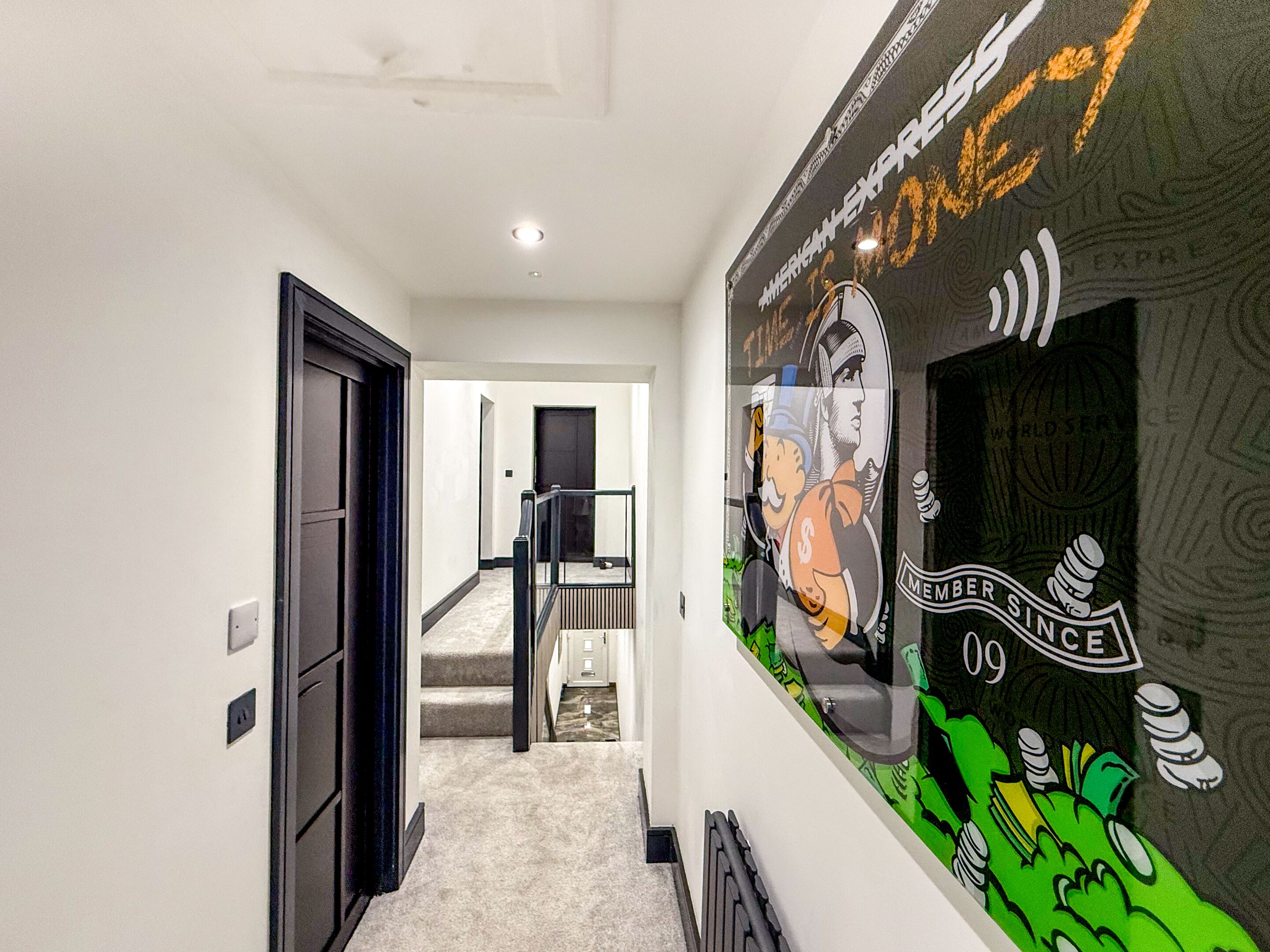 A hallway with a mural, a staircase, and a door.