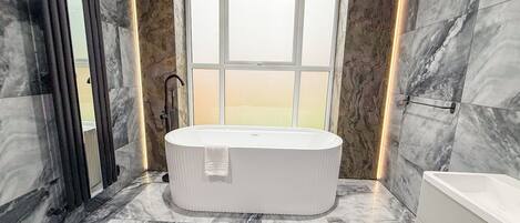 A modern bathroom with a freestanding bathtub, a shower area, and a large window providing a view.