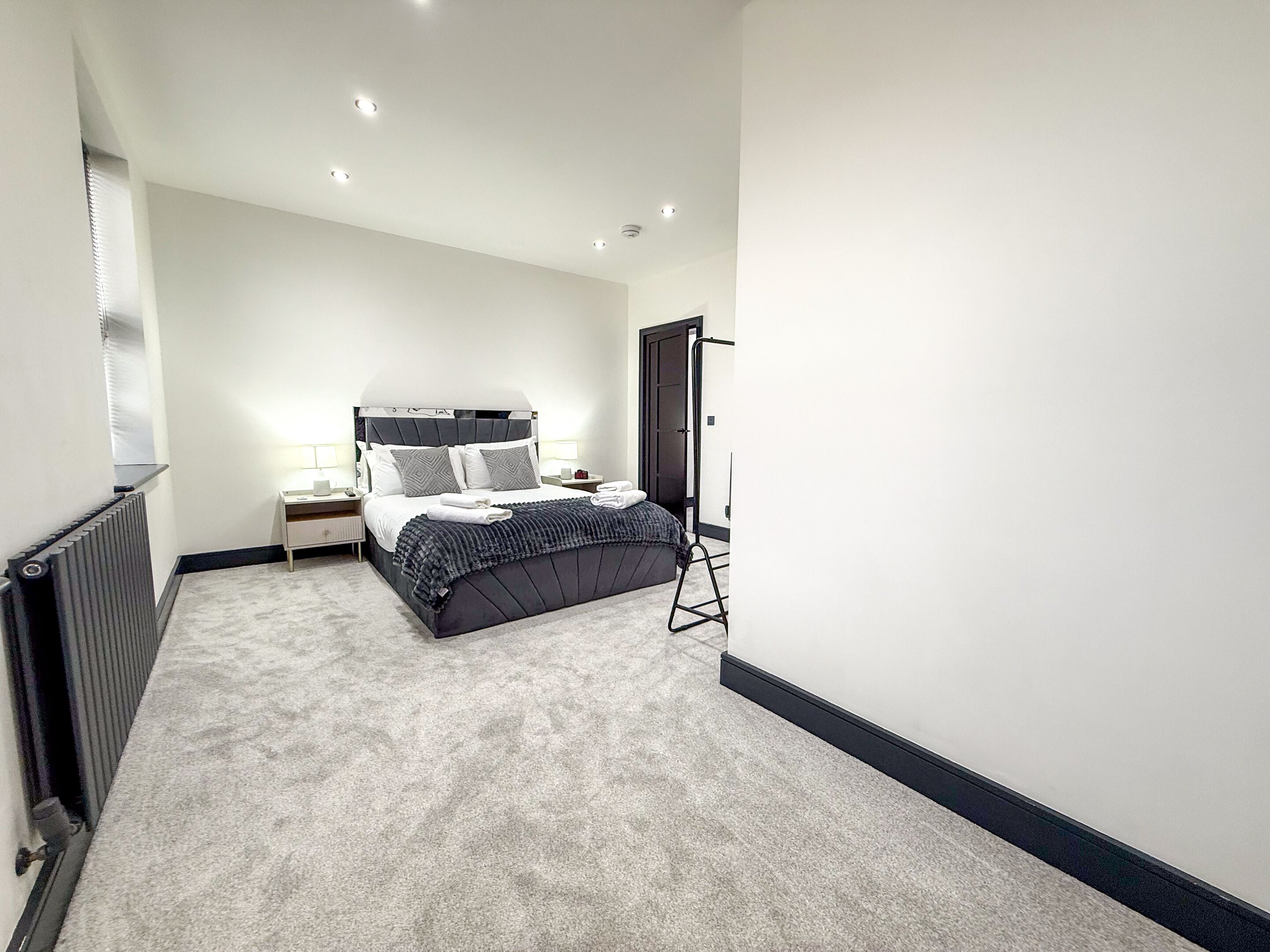 Una camera da letto moderna con un letto grande, comodini, un termosifone e una porta.