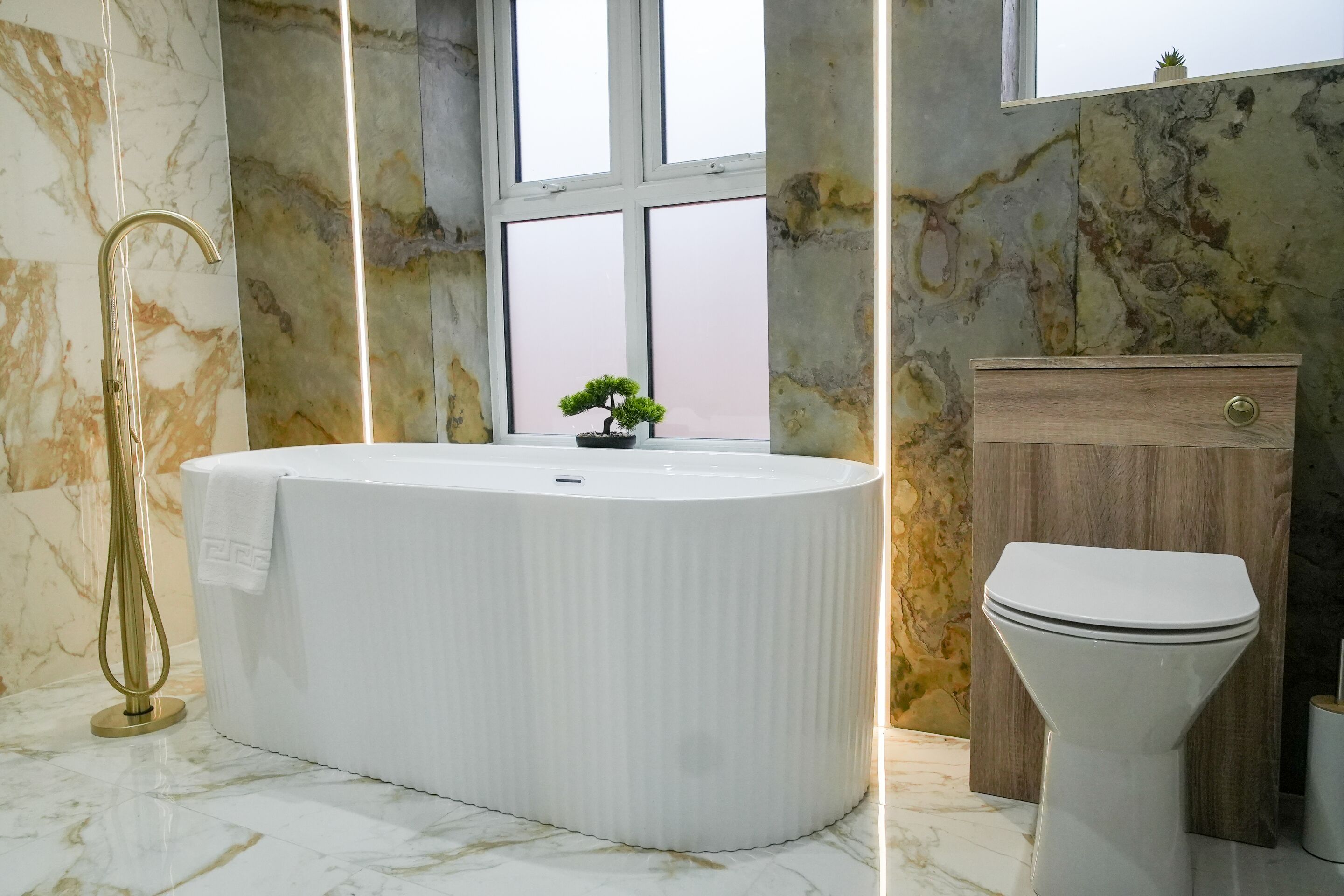 A modern bathroom with a freestanding bathtub, a toilet, and a wooden cabinet.