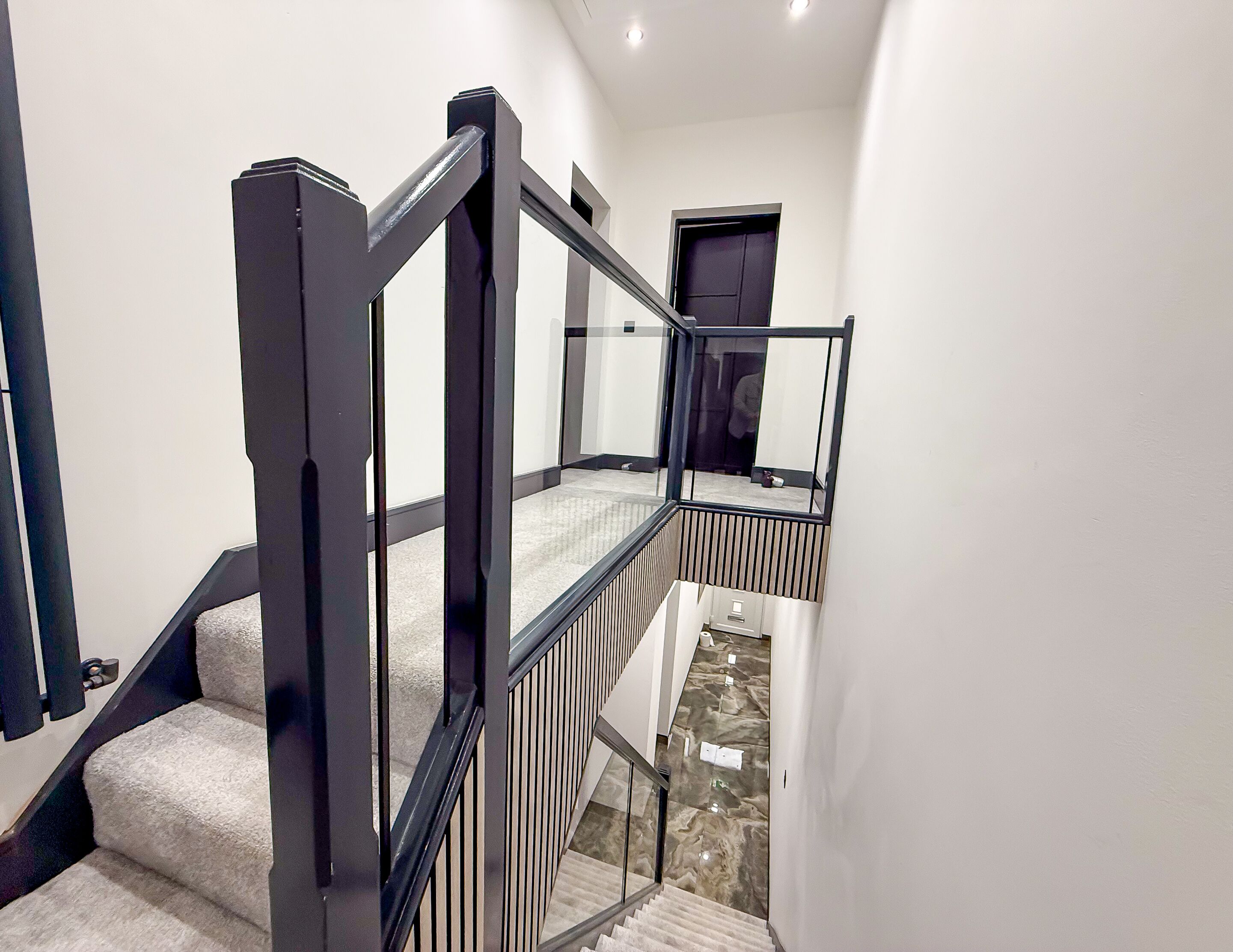 A modern staircase with black railings and a carpeted landing.