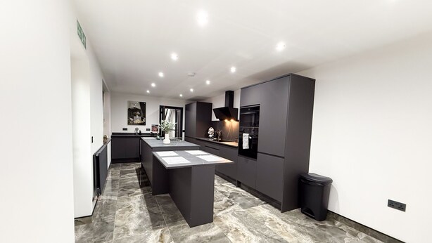 A modern kitchen with dark cabinetry, a marble floor, and recessed lighting. - Santi House (Boston)