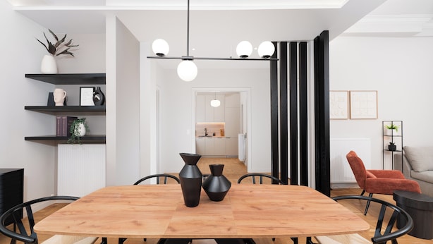 A modern dining area with a wooden table, black chairs, and two black vases. There is a black and white striped partition, a red chair, and a small round table with a plant.