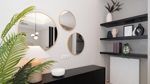 A modern interior with a black console, three mirrors, a white radiator, and shelves with decorative items.