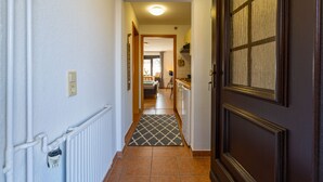 A narrow hallway with a radiator, a patterned rug, and a dark wooden door. - Dreamlike apartment house on the lakeshore port side (Waren (Müritz))
