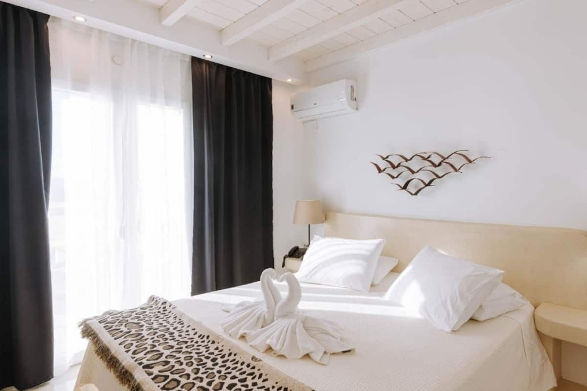 Habitación de hotel con cama, dos mesitas de noche, aire acondicionado de pared y un adorno mural.