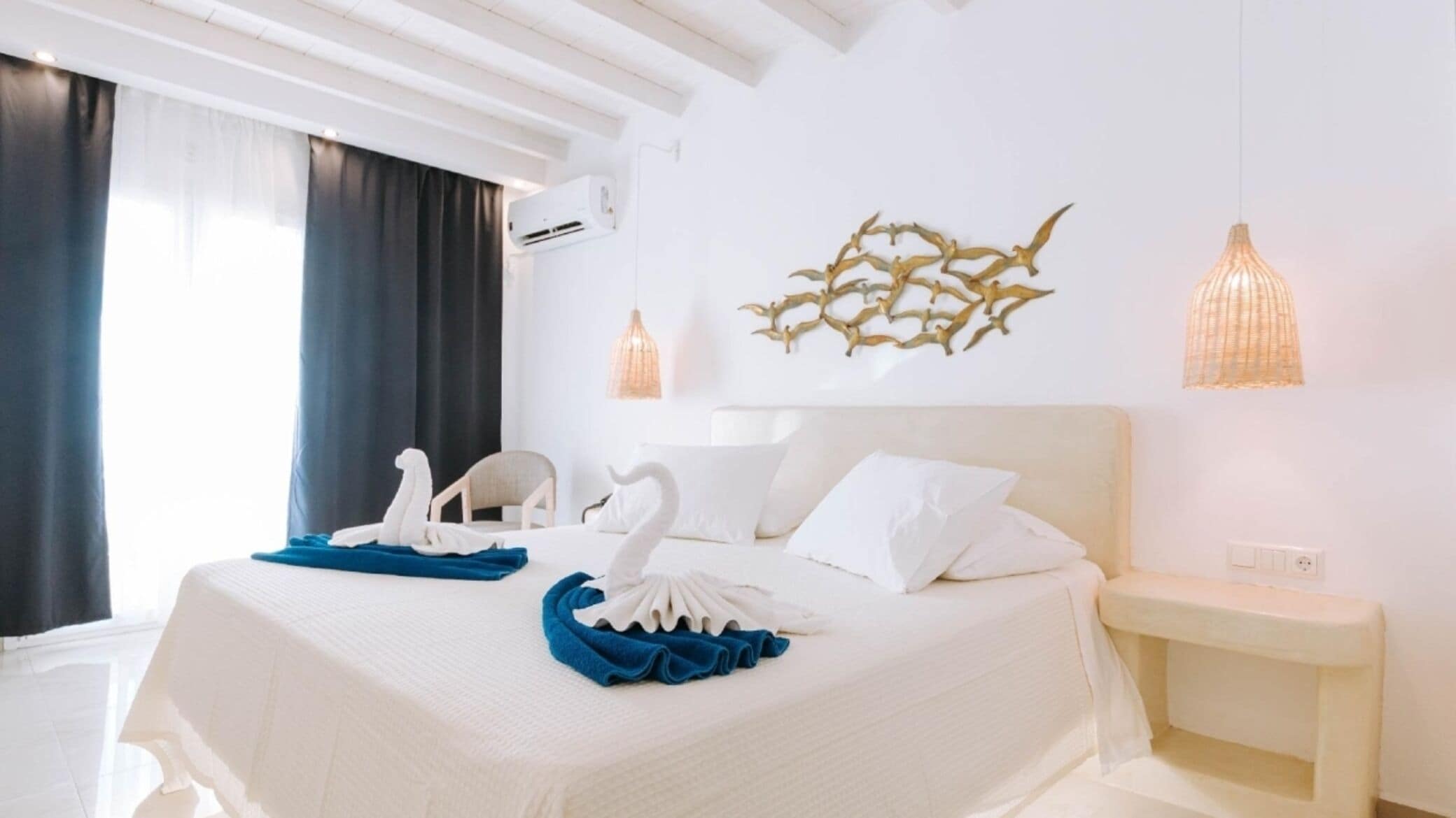 Una habitación de hotel con una cama, una mesita de noche, aire acondicionado en la pared y un adorno mural.