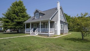 Une maison à deux étages avec un porche, une cheminée et une pelouse bien entretenue.