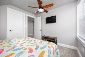 A bedroom with a bed, a ceiling fan, a TV, and a desk. - 4BR house - West OC, Harbor /Assateague- sleeps 9 (Ocean City)