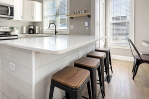 A modern kitchen with a large island, bar stools, and a coffee machine. - 4BR house - West OC, Harbor /Assateague- sleeps 9 (Ocean City)
