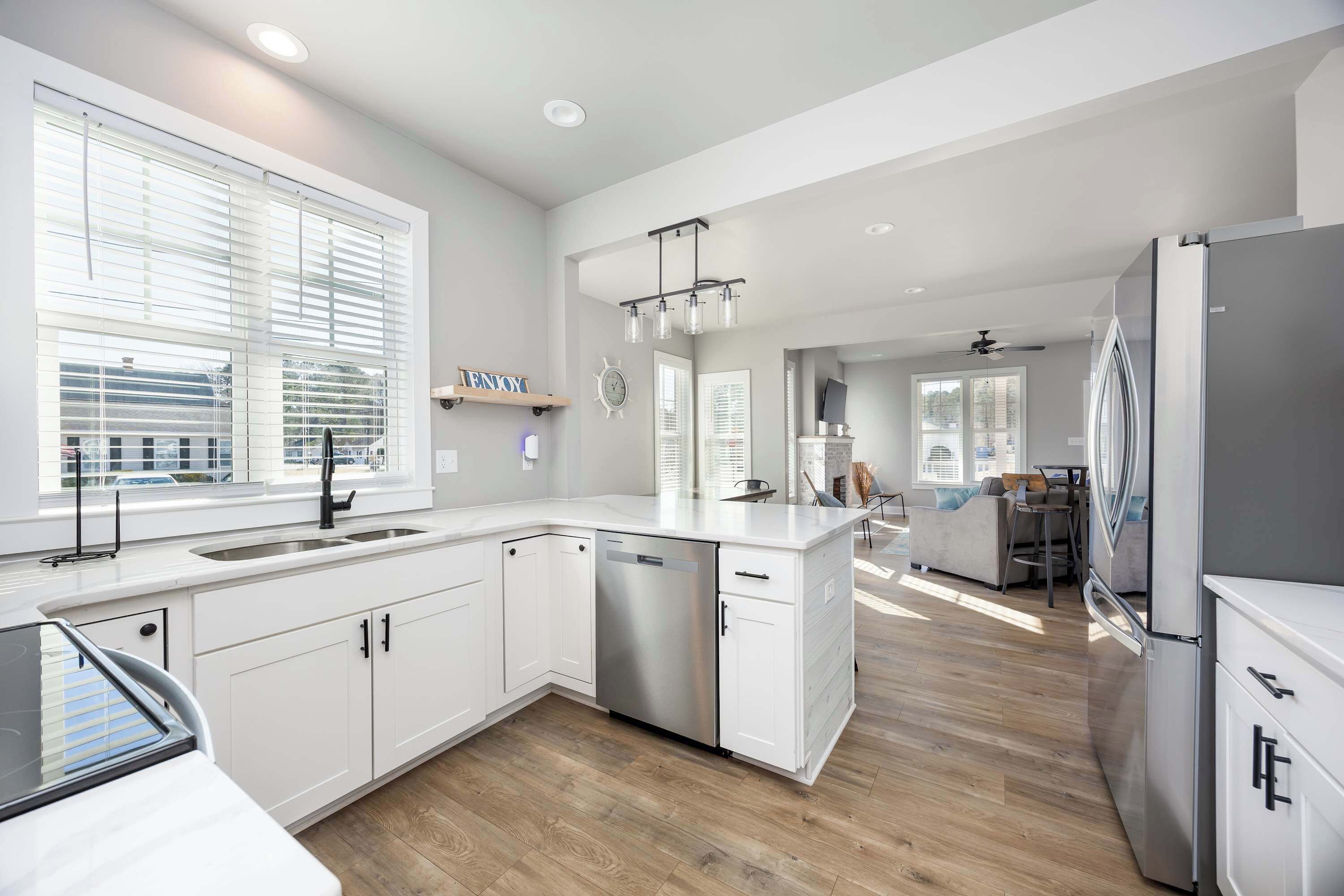 A modern kitchen with white cabinetry, stainless steel appliances, and a wooden floor.