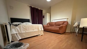 Una habitación con una cama, un sofá de cuero, una mesita y una silla.