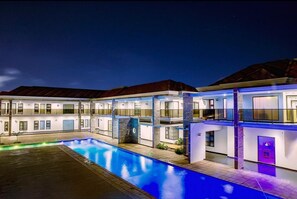 A modern hotel with a swimming pool, multiple balconies, and a well-lit facade. - Platinum Lodge (Matola)