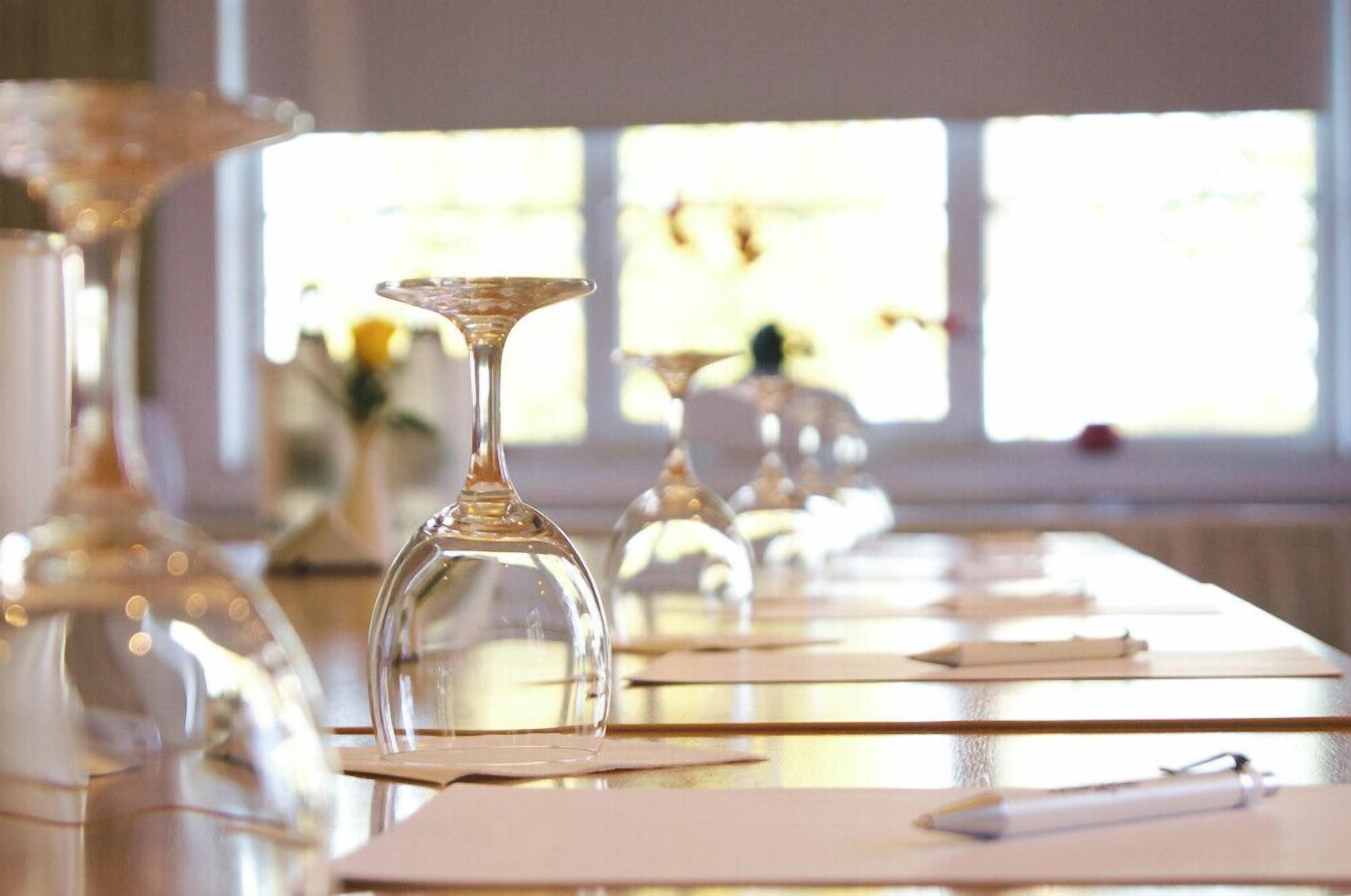 Ein Tisch ist gedeckt mit klarem Glas und Papierservietten, im Hintergrund ist ein Fenster zu sehen.