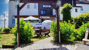 A courtyard with a wooden pergola, a picnic table, and a beer tent. - Fürstenhof Landgasthaus und Hotel (Erfurt)