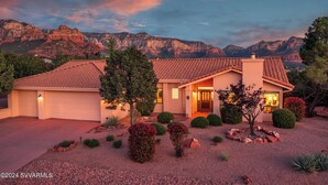 A single-story house with a tiled roof, a garage, and a well-maintained front yard with various shrubs and a tree. - 5 Bed, 3 Bath Uptown Sedona-Game Room-Sauna-Cold Plunge-Jacuzzi-Gym (Sedona)