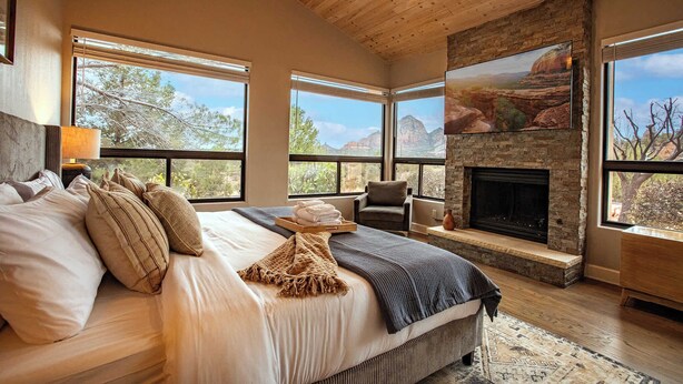 A bedroom with a large bed, a fireplace, and a view of the mountains. - 5 Bed, 3 Bath Uptown Sedona-Game Room-Sauna-Cold Plunge-Jacuzzi-Gym (Sedona)