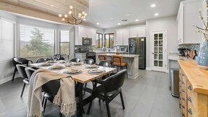A modern kitchen with white cabinets, a wooden ceiling, and a dining area with a table set for four. - 5 Bed, 3 Bath Uptown Sedona-Game Room-Sauna-Cold Plunge-Jacuzzi-Gym (Sedona)