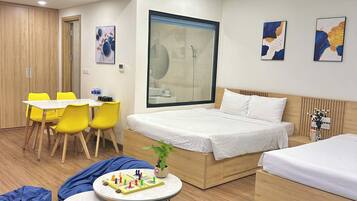 A modern hotel room with a bed, two bedside tables, a desk with chairs, a shower, and artwork on the walls.