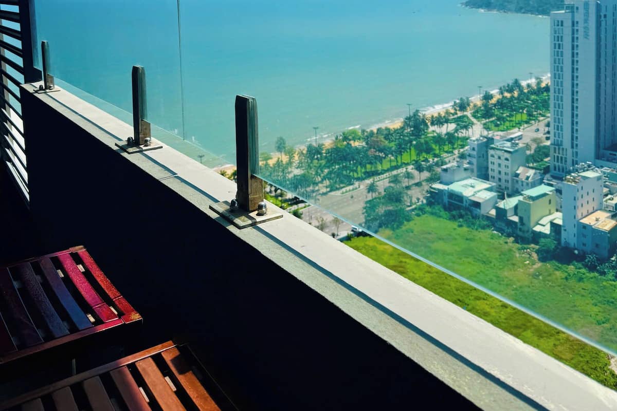 A balcony with a clear view of the sea and a cityscape.
