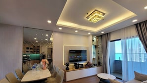 Un salon moderne comprenant un coin repas, un téléviseur à écran plat et une vitrine contenant des bouteilles.