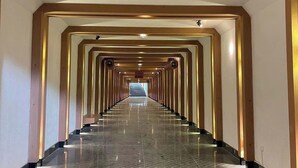 Un long couloir étroit doté d’un sol réfléchissant et d’une série de colonnes régulièrement espacées.