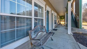 A covered outdoor area with a bench, large windows, and a staircase leading to an upper level. - Colonial Crest Condo Unit #113 (Pigeon Forge)