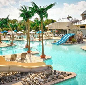 A swimming pool with a slide, lounge chairs, and palm trees.
