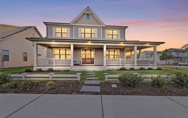 A two-story house with a front porch, a garage, and a well-maintained lawn.