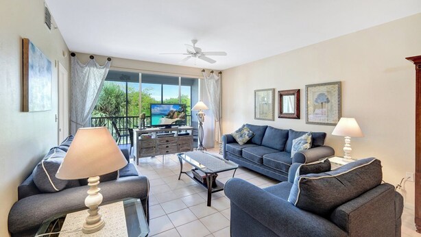 A living room with a sofa, armchairs, a coffee table, and a TV. There is a balcony with a view of the sea. - Vanderbilt Villas (Naples)