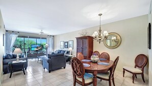 A spacious living room with a dining area, large windows, and a view of the outdoors. - Vanderbilt Villas (Naples)