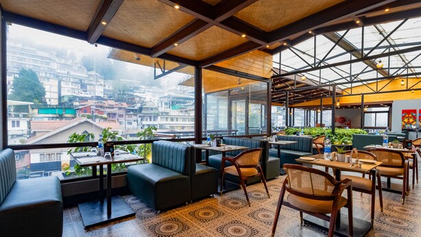 A modern restaurant with a terrace overlooking a cityscape. - Sumitel JB Park Darjeeling  (Darjeeling)