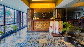 A reception area with a wooden counter, a stone wall, and a patterned floor. - Sumitel JB Park Darjeeling  (Darjeeling)