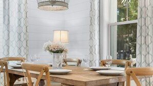 Una mesa de comedor de madera con seis sillas, un florero con flores y una lámpara en la pared.