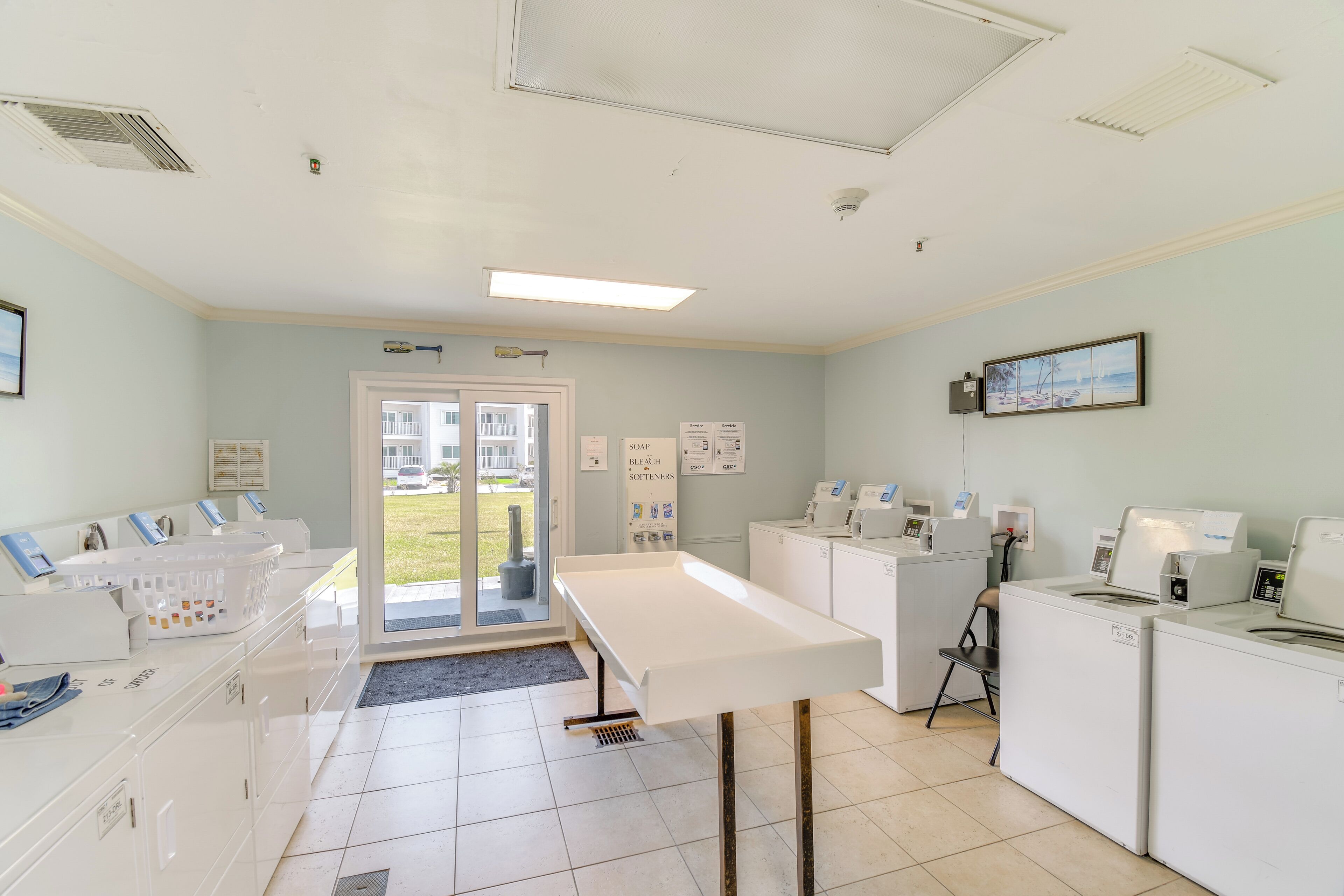 A laundry facility with multiple washing machines, dryers, and a folding station.